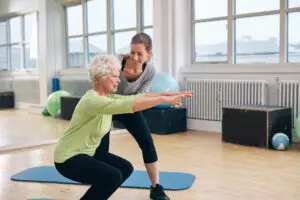 fitness coach helping an elderly woman exercise