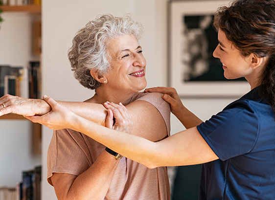 an elderly woman stretching with the help of a nurse