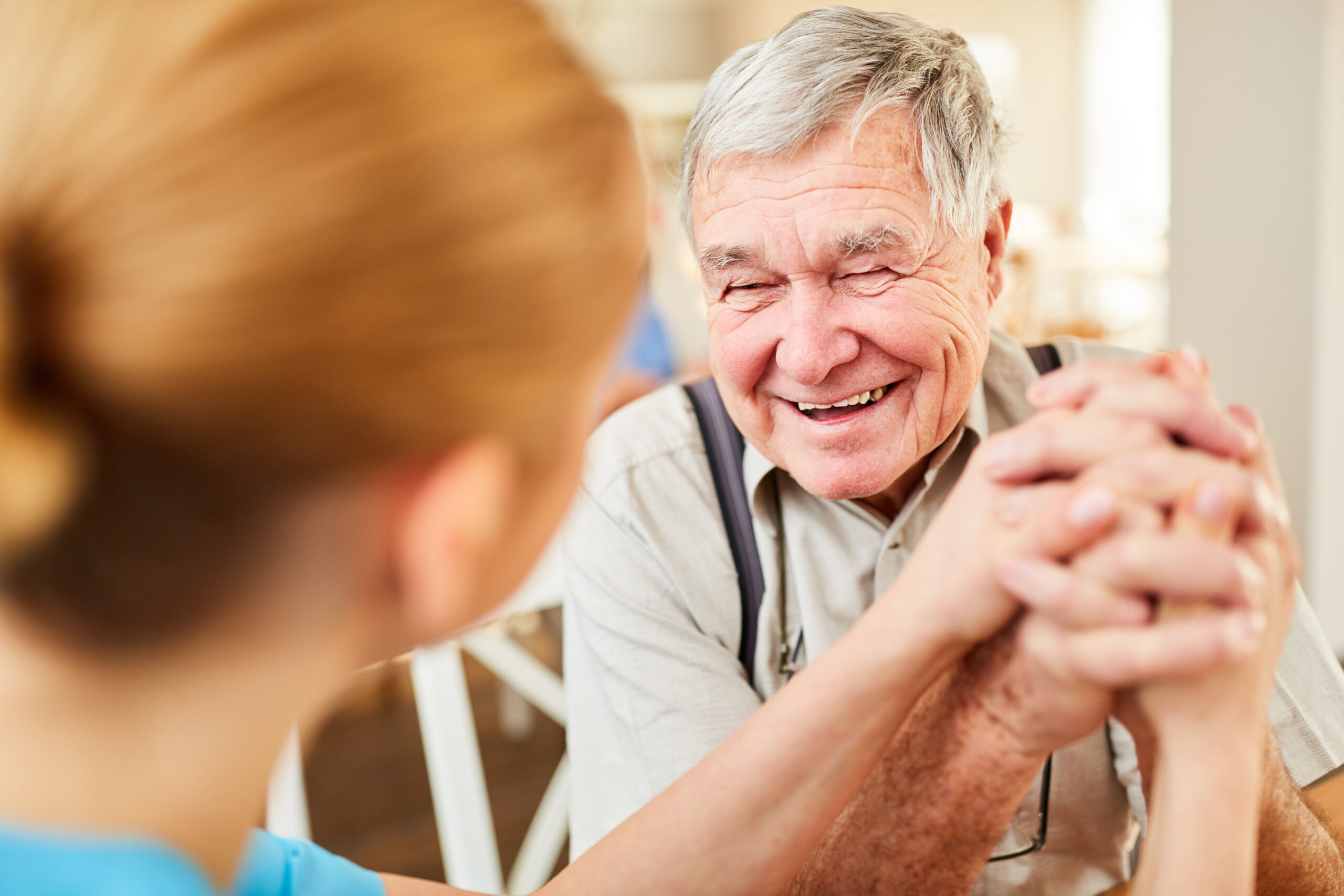 elderly man holding the hand of his nurse
