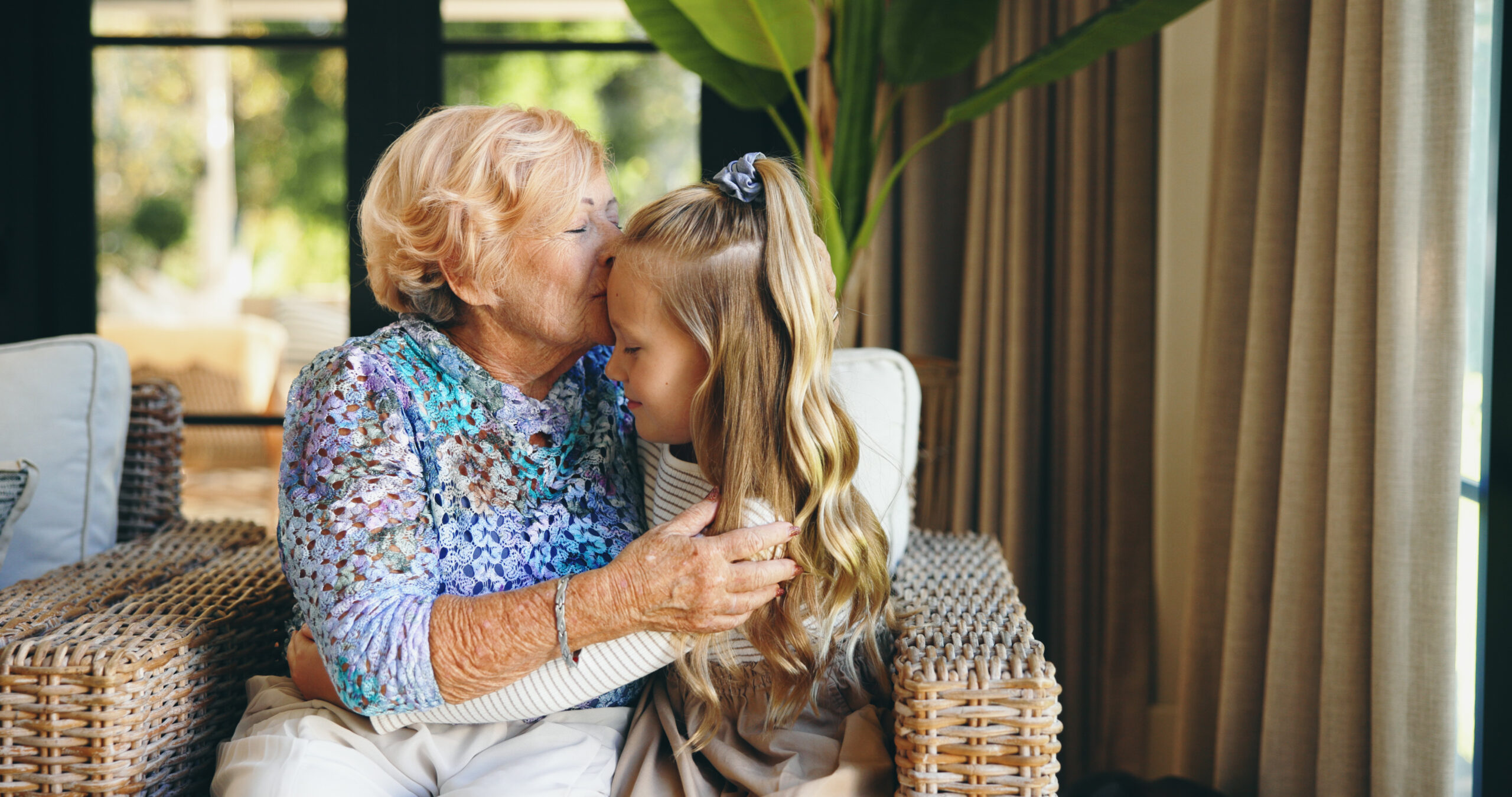 Elderly woman kissing her grandaughter on the forehead