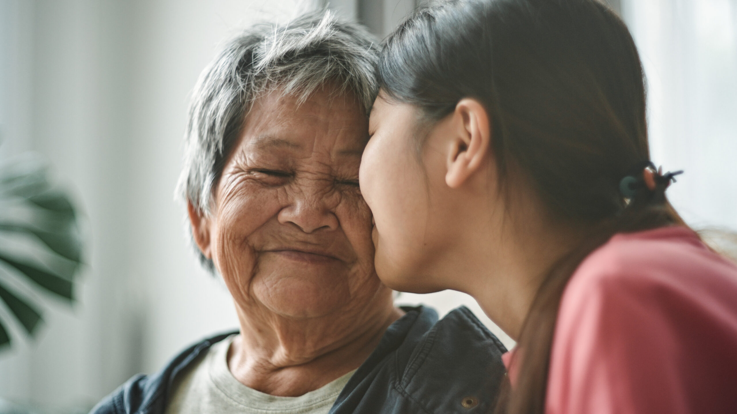 Asian senior woman relax talking with her granddaughter on sofa at home.